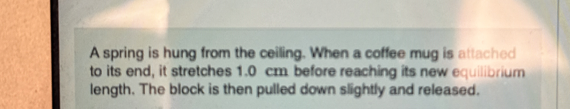 A spring is hung from the ceiling. When a coffee